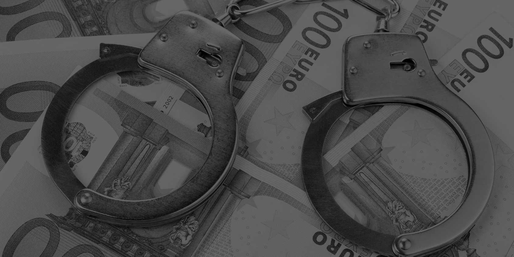 Handschellen liegen auf Geldschein, bildlich für Freiheitsstrafe und Geldstrafe im Strafrecht auch in Dortmund